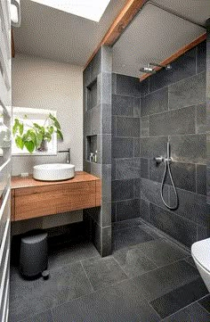 a modern bathroom with grey tiles and wood accents, including a skylight above the sink