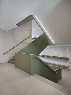 an empty room with some stairs and green railings on the wall next to it