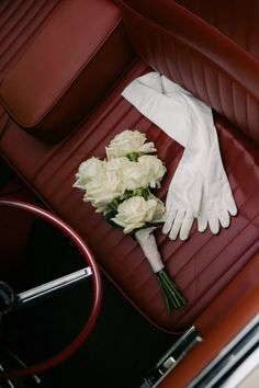 a bouquet of white flowers sitting on top of a red leather seat in a car