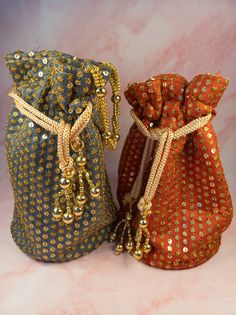 two bags with gold sequins on them sitting next to each other in front of a pink background