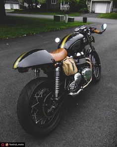 a black and yellow motorcycle parked on the side of a road in front of some houses