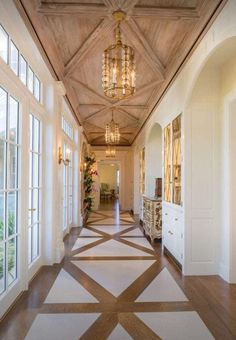 an elegant hallway with chandelier and large windows