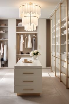 a white and beige closet with chandelier hanging from it's ceiling next to a counter