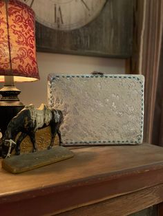 a cow figurine sitting on top of a wooden table next to a lamp