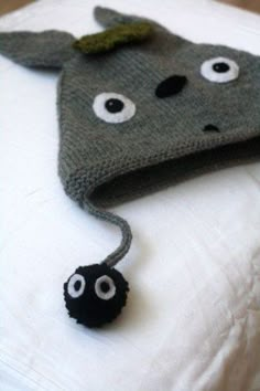 a knitted hat with googly eyes on top of a white blanket and two black balls