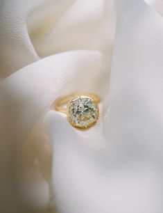 a yellow diamond ring sitting on top of a white cloth