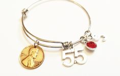 "Want the perfect gift for that special someone's double nickel 55th birthday or anniversary? This personalized stainless steel bangle comes with 1. a real US penny from the year they were born, 2. the corresponding number charm, 3. their birthstone and 4. their initial. This unique bracelet will show her how much thought you put into her milestone year! For small additional charge, you may also add charms like a birthday cake, happy birthday heart, happy anniversary, cup cake, or a gift charm. Classic Engraved Charm Bracelet For Anniversary, Stainless Steel Jewelry Hallmarked For Anniversary, Stainless Steel Jewelry With Hallmark For Anniversary, Classic Personalized Charm Bracelet For Anniversary, Personalized Metal Charm Bracelet For Anniversary, Classic Adjustable Charm Bracelet For Anniversary, Nickel-free Jewelry For Anniversary, Anniversary Metal Charm Bracelet, Silver Charm Bracelet With Birthstone For Anniversary