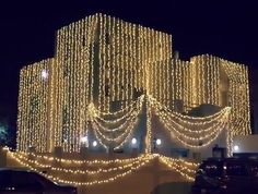 a large building covered in lots of lights and string lights on it's side