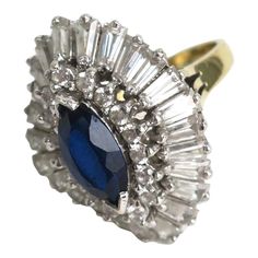 This is part of Chairish’s Costume Jewelry assortment.  An impressive vintage designer cocktail ring attributed to Benedetto Panetta, circa mid-20th century, 1960s. This cocktail ring is comprised of faux-diamonds and a single marque blue faux-sapphire, all set in sterling silver with gold wash on the rings' shank/band. The rings center marque stone is surrounded by round brilliant cut faux-diamonds and then tapered baguettes. The color of the center marque stone is a deep saturated blue hue, wi Vintage Multi-stone Cluster Ring For Anniversary, Vintage Multi-stone Diamond Rings, Vintage Marquise Sapphire Ring For Formal Occasions, Vintage Multi-stone Cluster Ring For Formal Occasions, Vintage Multi-stone Sapphire Ring, Vintage Gemstone Cluster Ring, Vintage Brilliant Cut Jewelry For Evening, Vintage Jewelry With Brilliant Cut For Evening, Vintage Sapphire Cluster Ring For Formal Occasions