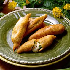 three fried food items on a plate with flowers in the backgroung area