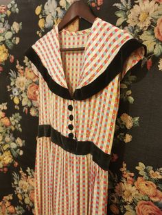 Lovely home-sewn cotton dress with faded black velvet trim waistband, covered buttons, and sailor-style collar. Perfect for late summer days or for layering over thermals and paired with a chunky knit as temperatures drop. The lightweight cotton is printed in a recognizable 50s-style square motif in autumnal red, yellow, taupe, white, and Robin's egg blue. The dress could benefit from adding an invisible zipper for ease of wear. Across chest 18 ½" Across waist 14" Across hip 25" Length from shou Retro Dress With Peter Pan Collar And Buttons, Retro Vintage Dress With Peter Pan Collar For Daywear, Vintage Collared Dress With Placket, 80's Clothes, Classic Costumes, Random Clothing, Oc Clothes, Roaring 20s Fashion, Radium Girls