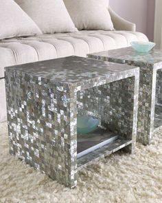 two silver mosaic side tables sitting on top of a white carpeted floor next to a couch