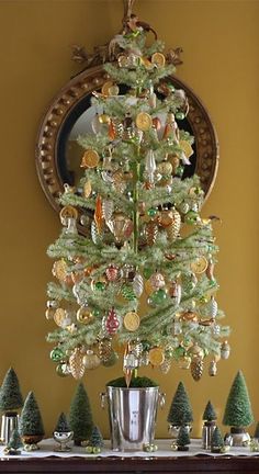 a small christmas tree is sitting on a mantel in front of a mirror and other ornaments