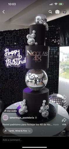 a three tiered cake with disco balls on top and happy birthday sign in the background