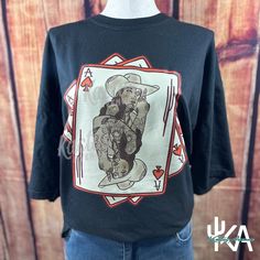 Embrace your wild side with this Vintage Grunge Cowgirl Tee, featuring a bold and unique Ace of Spades playing card design. Perfect for those who love to mix western vibes with a touch of edgy grunge, this graphic tee is a must-have for any wardrobe. Design Details: Ace of Spades Cowgirl: This one-of-a-kind graphic showcases a tattooed cowgirl in a classic playing card style, blending western charm with modern grunge. Unisex Fit: Designed to be worn by everyone, this tee offers a comfortable and Punk Style Graphic T-shirt For Fall, Unisex Hip Hop Top With Graphic Print, Hip Hop Tops With Funny Print And Short Sleeves, Hip Hop Short Sleeve Tops With Funny Print, Unisex Graphic Print Tops For Fan Merchandise, Punk Style Top With Front Print And Relaxed Fit, Punk Cotton T-shirt With Funny Print, Punk Style Cotton T-shirt With Funny Print, Hip Hop Cotton Tops With Funny Print