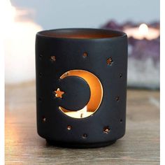 a black candle holder sitting on top of a wooden table next to a lit candle