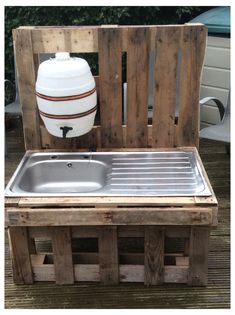 an outdoor sink made out of wooden pallets with a large white container on top