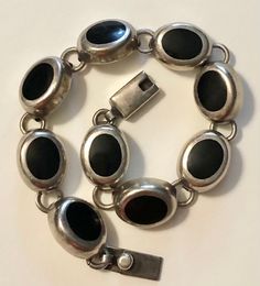 This is a really lovely vintage Mexican 950 (higher silver content than traditional sterling silver) bracelet dating to the 1960s-70s. The bracelet has a box slide clasp and is comprised of 9 oval silver and onyx links, each incredibly well constructed and attached to one another. It's signed on the clasp: MEX 950 HOB, which I have come to learn means it was made by a company called HOUSE OF BANGLES. On the larger side, this would be best for a medium to large woman's wrist. I have a medium/smal Vintage Round 925 Stamped Bracelets, Vintage 925 Stamped Bracelet, Hallmarked Vintage Sterling Silver Bracelet, Vintage Hallmarked Sterling Silver Bracelet, Silver Oval Bracelets For Collectors, Adjustable Vintage Bracelets Stamped 925, Adjustable Vintage Stamped 925 Bracelets, Adjustable Vintage 925 Stamped Bracelets, Mid-century Adjustable Silver Jewelry