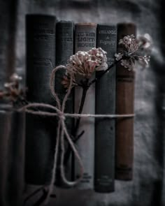 some books are tied to a wall with flowers on them, and one is in front of the bookcase