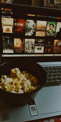 a bowl of popcorn sitting on top of a laptop computer