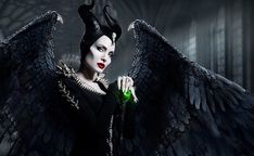 a woman dressed as maleficent with black wings holding a green bottle in her hand