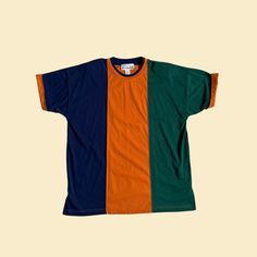 "Vintage 90s color block t-shirt, manufactured by Carolina Colours II. Originally a women's size 20W / 40, but could be worn by anyone today. Dark blue, dark green, and orange colorblock / vertical striped design. Features cuffed sleeves and shoulder pads.    - Brand: Carolina Colours II    - Size: Size 20W / 40    - Time Period: 1990s    - Color(s): Dark blue, dark green, orange    - Materials: Polyester, cotton    - Made in: Hong Kong    - Condition: In new old stock condition; still has a par Green T-shirt With Contrast Color For Summer, Retro Cotton T-shirt With Contrast Color, Sporty Multicolor Color Block T-shirt, Retro Cotton Tops With Contrast Color, Multicolor Contrast Cotton Shirt, Multicolor Cotton Shirt With Contrast Color, Retro Color Block T-shirt For Streetwear, Green Crew Neck Top With Patchwork, Green Patchwork Crew Neck Top