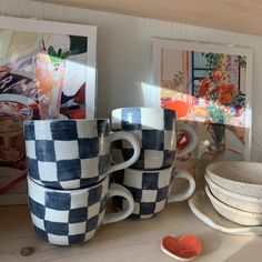 several cups and plates are stacked on a table with pictures in the backround