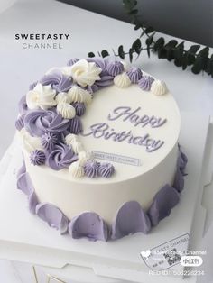 a white and purple birthday cake with flowers on it