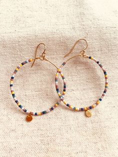 This listing is for one pair of beaded hoop earrings.  The beads are Miyuki Delicas Japanese glass beads.  Bead colors: Blue, Turquoise, baby blue, light pink, mauve, ochre  The ear wire and hoop wire are gold filled.  The gold blank charm that dangles at the bottom of the hoop is gold vermeil.  These earrings are light on the earlobe and add a pretty pop of color and movement!  Measurement: from the top of the ear wire to the bottom of the vermeil round charm is 2 1/4 inch.  What is Gold Filled Adjustable Circular Beaded Earrings With Tiny Beads, Adjustable Hoop Beaded Earrings With Dangling Beads, Small Hoop Beaded Earrings For Everyday, Nickel-free Heishi Bead Hoop Earrings, Adjustable Hoop Earrings With Tiny Beads, Hoop Beaded Earrings With Spacer Beads, Small Hoop Beaded Earrings With Spacer Beads For Gifts, Small Hoop Beaded Earrings With Spacer Beads As Gift, Hoop Earrings With Dangling Round Beads For Gifts