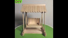 a wooden toy swing set sitting on top of a green surface with the words diy above it