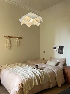 a bed sitting in a bedroom next to a wooden dresser under a hanging light fixture