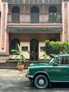 an old green car parked in front of a building