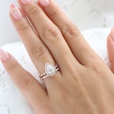 a woman's hand with a diamond ring on top of her finger and pink manicured nails