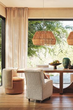 a dining room with chairs and a table in front of large windows that look out onto the outdoors