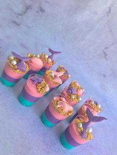 there are seven little mermaid cups with candy in them