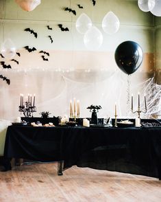 a table topped with lots of black and white balloons next to a wall covered in bats