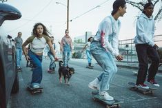 group of skateboarders riding down the street with their dogs