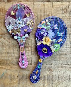 two decorative hairbrushes sitting on top of a wooden table