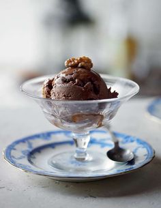 chocolate ice cream with walnuts in a glass bowl on a blue and white plate