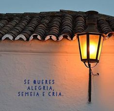 a street lamp on the side of a building with spanish words written on it at night