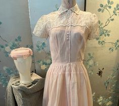 1950 vintage, pink organza dress with white embroidered leaves and flowers. The top has a high neck with a collar with 3 sets of white buttons, also in threes, down the front to the waist. The yoke over the shoulders, including the short sleeves, are embroidered.the hem of the full, gathered skirt is embroidered. The pink linen, circle hat is covered with pink netting decorated with pink leaves. The taffeta lining is strapless on the top. Bust 32", waist 26", bodice length 16", skirt length 33". 1950s Pink Vintage Wedding Dress, Feminine Pink Vintage Dress For Wedding, Feminine Pink Vintage Wedding Dress, Pink Organza Dress, Circle Hat, Embroidered Leaves, 1950 Vintage, Organza Dress, Pink Leaves