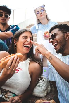 a group of young people eating hotdogs together