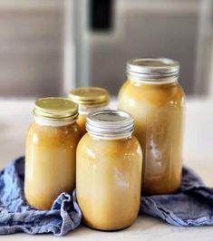 three jars filled with yellow liquid sitting on top of a blue towel next to each other