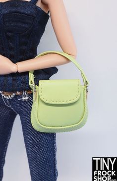 a doll is holding a small green purse