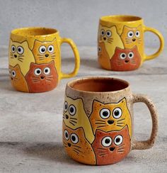 three yellow and orange mugs with cats painted on them