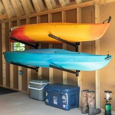 two kayaks are hanging from the ceiling in a garage with storage boxes and coolers