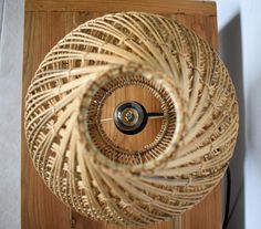 a clock made out of wicker sitting on top of a wooden table next to a wall