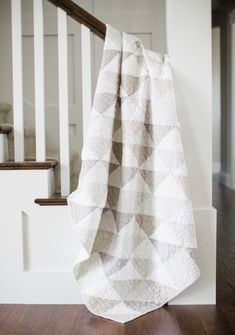 a white and brown blanket sitting on top of a wooden floor next to a stair case