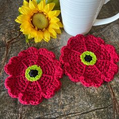 two crocheted flower coasters sitting next to a coffee cup on a table