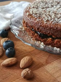 a cake sitting on top of a wooden table next to blueberries and almonds